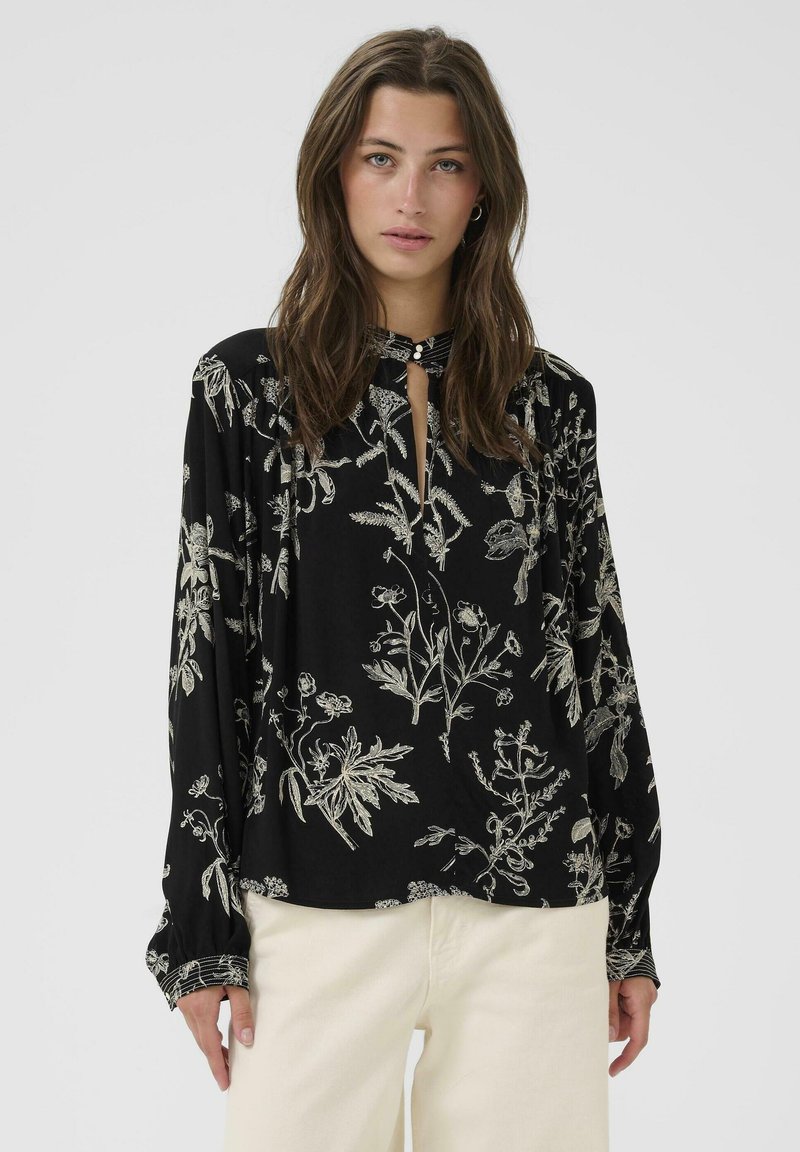 Schwarze Bluse mit weißer floraler Stickerei, langen Ärmeln, einem Schlüsselausschnitt mit Knopfdetail und gerafften Akzenten an den Manschetten.