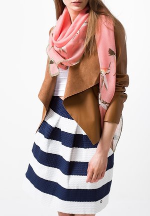 Femme portant une veste en cuir marron, une écharpe rose avec des motifs d'oiseaux, un haut blanc et une jupe rayée bleu marine et blanche.