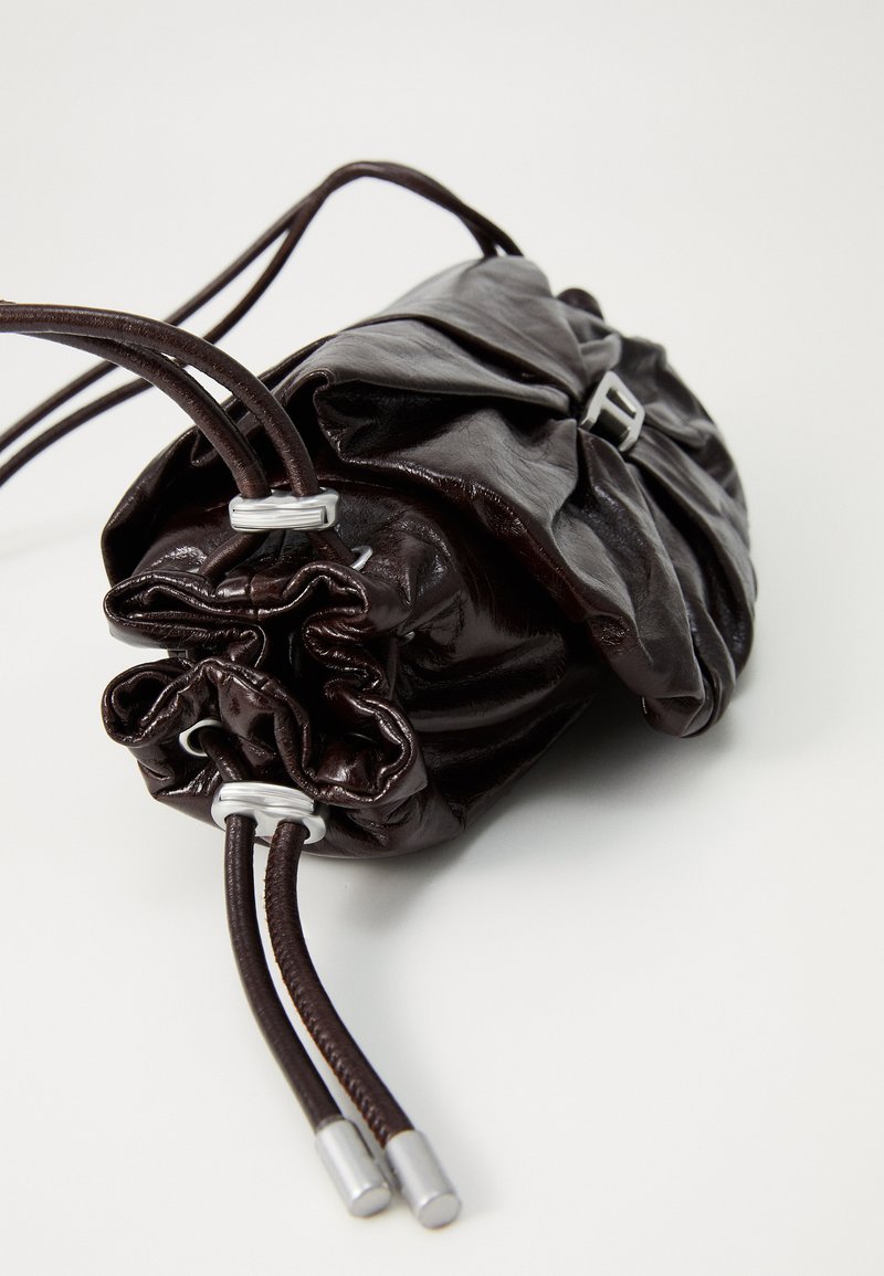 Dark brown glossy leather drawstring pouch bag with silver metal accents on the straps and front buckle closure.