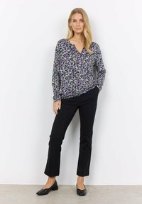 Floral blouse in purple, green, and white with a V-neck and long sleeves, paired with black straight-leg trousers and black flats.