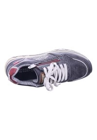 Scarpa atletica grigia con design perforato, lacci bianchi e dettagli rossi. Presenta una suola imbottita e una fodera interna a motivi.