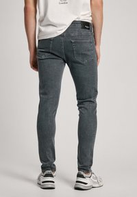 Tumedatest hallid slim-fit teksad tekstureeritud viimistlusega, tagatasku detailidega ja musta vöötähisega. Kandub koos valgete ja mustade spordijalatsitega.