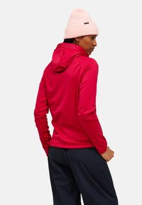 Rood hoodie met een gestructureerde afwerking, voorzien van een kangoeroezak en aansluitende mouwen, gecombineerd met een lichtroze gebreide beanie.