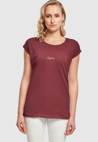 Burgunderfarget bomulls t-skjorte med oppbrettede ermer og rund hals, med ordet "Inspire." brodert i lys skrift på forsiden.