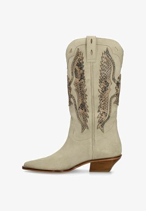 Beige suède cowboylaars met spitse neus, middelhoge schuine houten hak en bruine slangenhuidmotief vleugelborduursel op de schacht.