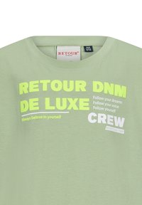 Jasnozielona koszulka z krótkim rękawem, okrągłym dekoltem, z odważnym białym i neonowożółtym napisem, w tym "RETROUR DNM DE LUXE" oraz "CREW."