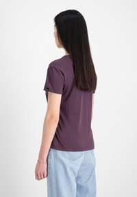 Lilla kortærmet t-shirt med rund halsudskæring, parret med lyseblå denim jeans. Glat stof og minimalistisk design.