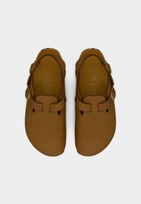 Ζευγάρι καφέ δερμάτινων πάνινα παπούτσια με ρυθμιζόμενα λουριά με αγκράφα σε λευκό φόντο, μέγεθος 38 εμφανές εσωτερικά.