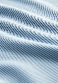 Tessuto di un blu chiaro con una trama visibile a coste, che crea onde morbide. Il materiale appare liscio, con una lucentezza sottile e un motivo uniforme.