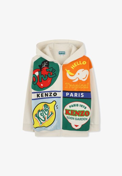 Sweat à capuche crème avec des impressions graphiques multicolores incluant des fruits et du texte. Présente un zip frontal et des couleurs d'accent contrastantes.