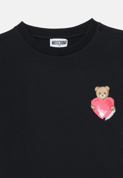 Μαύρο βαμβακερό μπλουζάκι με γραφικό αρκούδας που κρατάει μια ροζ καρδιά στην αριστερή πλευρά· στρογγυλή λαιμόκοψη με ριμπ τελείωμα· λογότυπο Moschino.