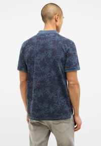 Granatowa koszulka polo z wzorem liści, z teksturowanej tkaniny i kołnierzykiem; kontrastowe wykończenie rękawów; luźny krój.