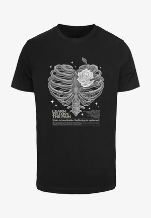 Sort t-shirt med et grafisk motiv af et skelet ribbenbur sammenflettet med en hvid rose, suppleret med tekst og dekorative stjerner.