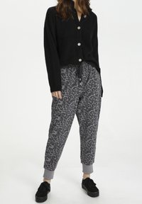 Sort fuzzy cardigan med sølvknapper, parret med grå leopardmønstrede sweatpants med justerbar snor i livet og ribbede cuffs.