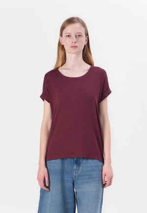 Maroon short-sleeve t-shirt with a round neckline and rolled sleeve cuffs. Made of a soft, textured fabric. Paired with loose denim jeans.