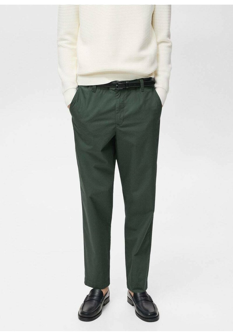 Green cotton trousers with a relaxed fit, featuring belt loops and side pockets. Paired with a white ribbed sweater and black loafers.