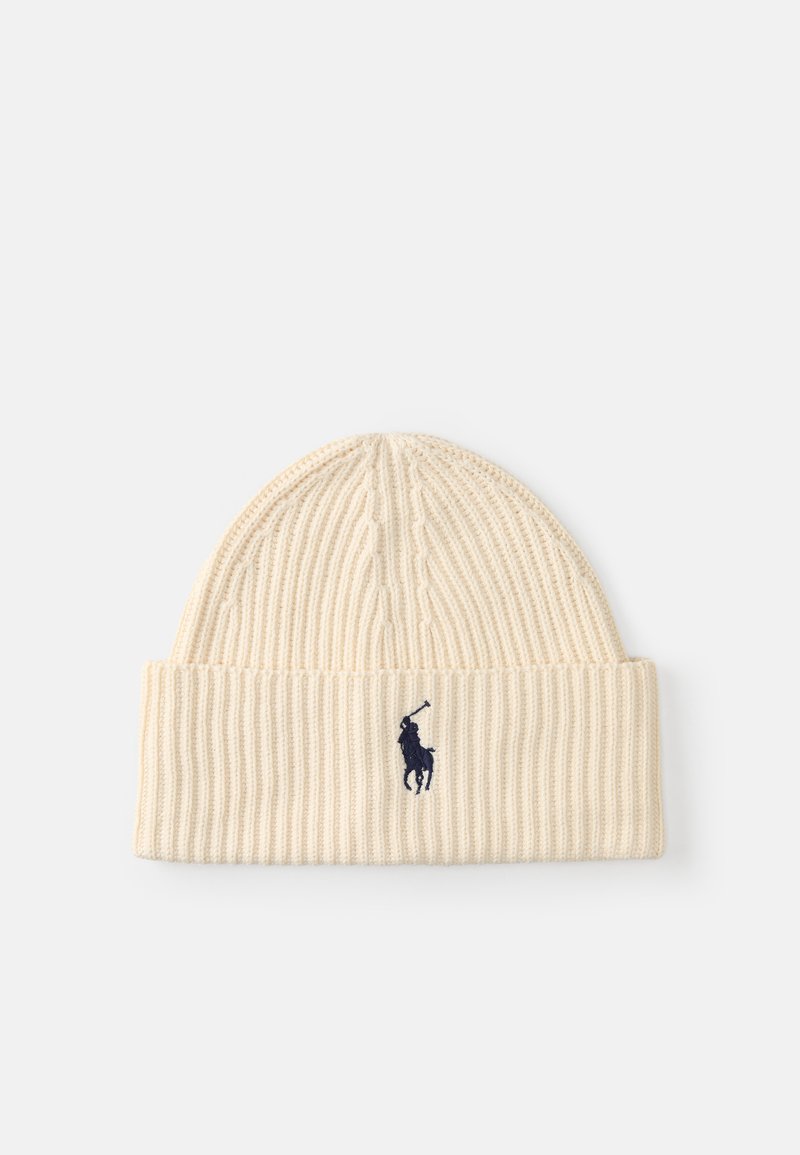 Gorro de malha canelada em creme com aba dobrada. Apresenta um logotipo em contraste em azul-marinho de um cavaleiro. Textura suave, design ajustado para aquecer.