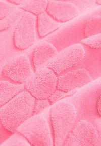 Rosa Textil mit strukturierten Blumenmustern und plüschigen Blütenblattformen, die eine weiche und taktile Oberfläche schaffen.