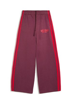 Pantalon de jogging bordeaux à jambes larges avec bandes latérales rouges et taille élastique, avec un texte rouge "RELOAD JUST CHILL" sur la cuisse gauche.