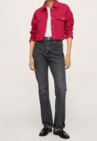 Fuksjowa pikowana kurtka z złotymi guzikami, w zestawieniu z czarnymi spodniami o prostym kroju z wysokim stanem i czarnymi butami. Pod spodem gładka biała koszulka.