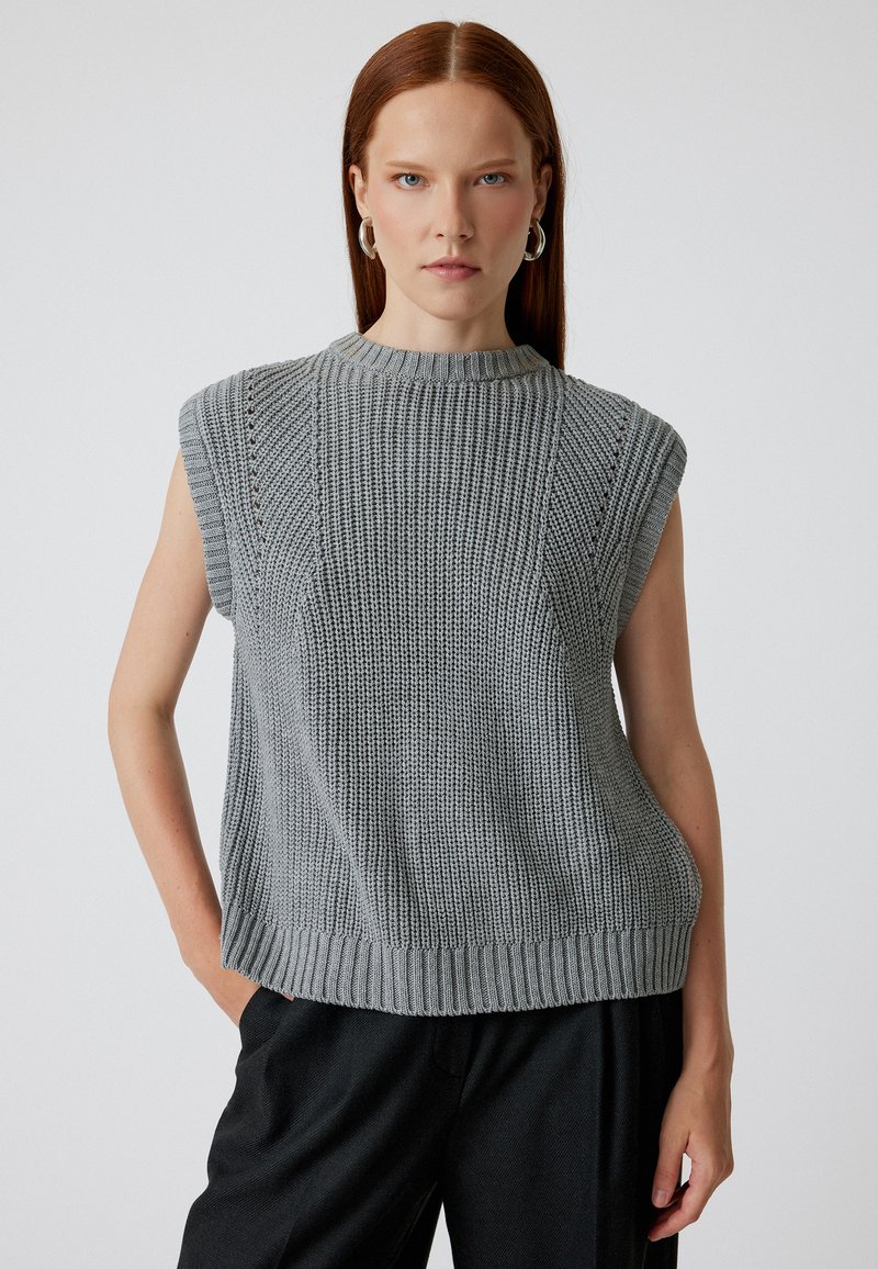 Top senza maniche grigio in maglia, con colletto alto, tessuto testurizzato e orlo a coste, caratterizzato da spalle leggermente definite e dettagli in lavorazione aperta.