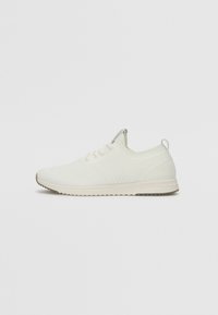 White athletic shoe with a textured knit upper, lace-up design, and a light-colored rubber sole featuring a patterned tread.