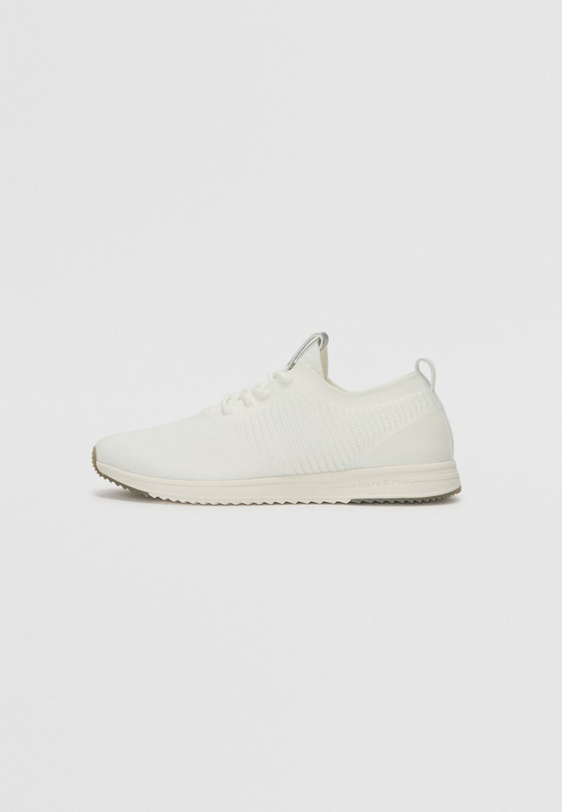 White athletic shoe with a textured knit upper, lace-up design, and a light-colored rubber sole featuring a patterned tread.