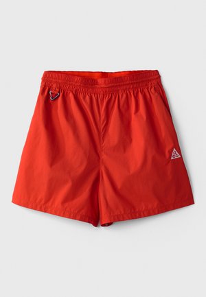 Røde, lette svømmedragt med elastisk talje, indbygget snor og en lille logoaccent nederst til højre.