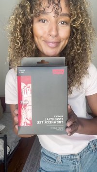 Caixa retangular preta com detalhe em vermelho, rotulada "Levi's Women's Essential Crewneck Tee," contendo um pack de duas unidades no tamanho pequeno.