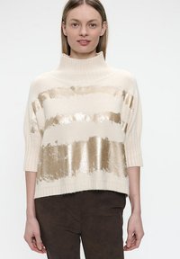 Cremefarbener Strickpullover mit hohem Kragen, der horizontale goldene Folienstreifen, kurze Ärmel und strukturiertes Rippmuster an den Bündchen und dem Saum aufweist.