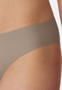 Light brown bikini bottom featuring a smooth, matte texture with a wide band. The design is minimalistic and seamless for comfort.