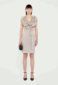 Világos rózsaszín ruha fodros nyakkivágással, feszes derékkal és megkötős övvel. Az anyag textúrált, és finom fényességgel rendelkezik. Fekete kiegészítők teszik teljessé a megjelenést.