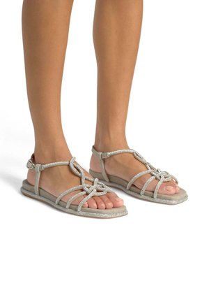 Zilveren glinsterende sandalen met een platte zool, voorzien van een geknoopt ontwerp en verstelbare enkelbandjes, met een zachte, gestructureerde afwerking.