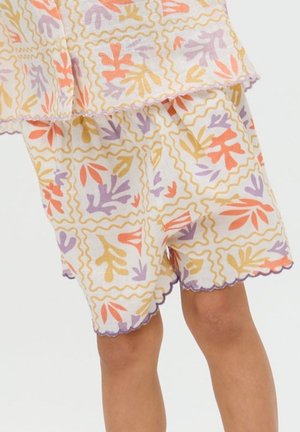 Gehäkelte Shorts mit abstrakten Blattmustern in Orange, Gelb und Lila auf weißem Hintergrund, getragen von einem stehenden Kind.