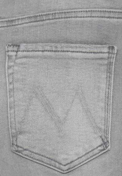 Tessuto di denim grigio che mostra la tasca posteriore di un jeans, caratterizzato da un motivo di cucitura a contrasto con un sottile design triangolare sopra la tasca.