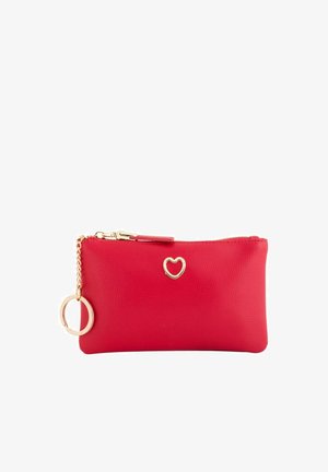 Petit sac rouge texturé avec un emblème en forme de cœur doré, fermeture éclair et porte-clés doré fixé par une petite chaîne.