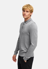 Graues langärmliges Polo-Shirt mit Kragen und einer Knopfleiste mit drei Knöpfen. Der Stoff wirkt weich und strukturiert und ist an den Bündchen gerippt.
