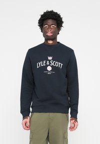 Navy crewneck sweatshirt featuring "LYLE & SCOTT" logo in white with a crown and rose graphic, made of soft cotton blend fabric.
