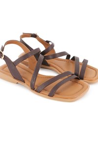 Sandalias de cuero marrón con múltiples tiras entrecruzadas, diseño de punta cuadrada y una plantilla color tostado. Incluyen un cierre de hebilla en la correa del talón.