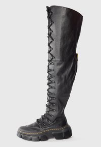 Knee-high black leather lace-up boots with chunky rubber sole, featuring a textured finish and yellow stitching detail.