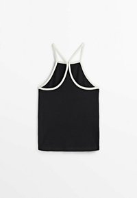 Top crop sans manches noir avec des bordures blanches et de fines bretelles croisées sur fond blanc.