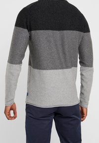 Langarm-Sweatshirt mit Farbblockdesign in Schwarz, Dunkelgrau und Hellgrau. Hergestellt aus strukturiertem Strickstoff, mit abgerundetem Saum.