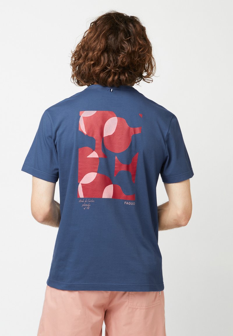 T-shirt bleu marine avec un motif graphique en rouge et rose au dos, présentant des formes abstraites. Tissu en coton doux, manches courtes.