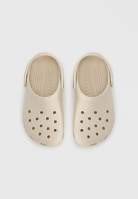 Μπεζ λαστιχένια τσόκαρα με λεία υφή, πίσω λουράκι και πολλαπλές οπές αερισμού για αναπνευσιμότητα. Εργ ονομικός σχεδιασμός και στυλ που φοριέται εύκολα.