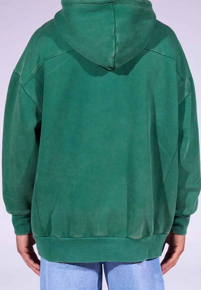 Felpa verde con cappuccio, in materiale misto cotone, vestibilità ampia, cappuccio grande, polsini e orlo a costine, caratterizzata da una superficie strutturata con variazioni distinte di colore.