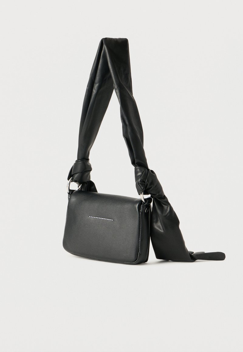 Sac bandoulière rectangulaire noir avec une sangle torsadée nouée et un détail subtil de couture horizontale sur le rabat avant.