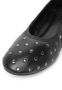 Czarne skórzane baleriny z zaokrąglonym noskiem, zdobione metalowymi ćwiekami równomiernie rozmieszczonymi na górnej powierzchni.