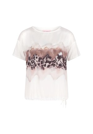 Blouse blanche à manches courtes avec bande à imprimé léopard abstrait marron et texte métallique indiquant "Parfois, moins c'est plus" sur la poitrine.