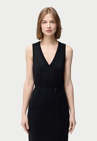 Svart ärmlös klänning med djup V-ringning, tygbälte i midjan, fickor på båda sidor och mjuk textur.