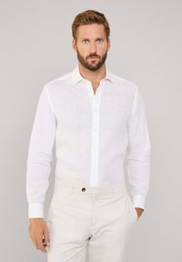 Witte linnen overhemd met lange mouwen en een button-down kraag, met een voorpand voorzien van knopen en een textuurstof. Gecombineerd met lichte broek.